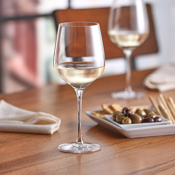 A Nude Refine white wine glass of wine on a table.