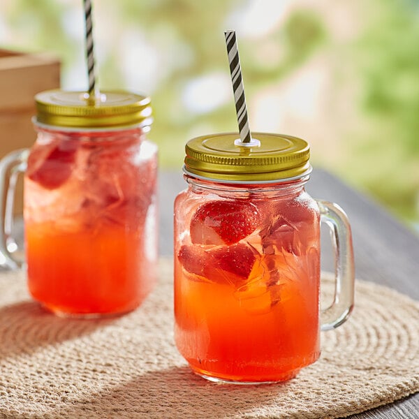 Two Acopa Rustic Charm glass jars with red drinks and straws on top.