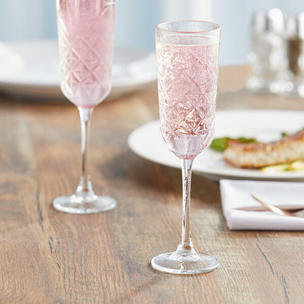 Two Pasabahce Timeless Vintage champagne flutes of pink liquid on a table.