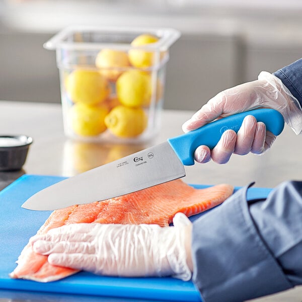 A person in gloves using a Choice 8" Chef Knife to cut a lemon.