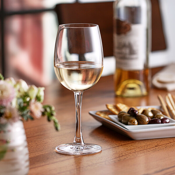 A Nude Reserva wine glass filled with white wine sits on a table.