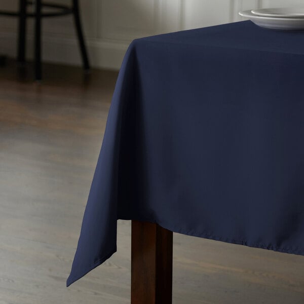 A wooden table with an Intedge navy blue rectangular tablecloth.