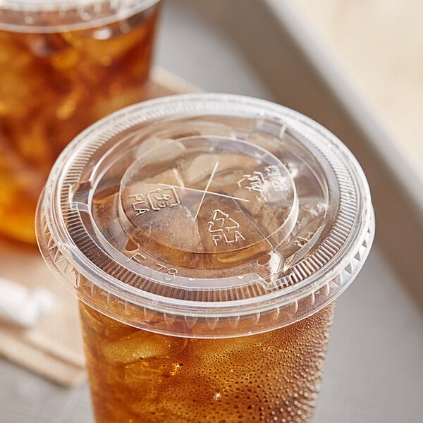 A plastic EcoChoice cold cup lid with a straw slot over a drink in a clear plastic cup.