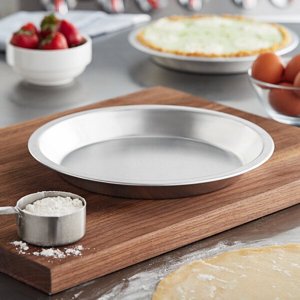 A close up of a Choice aluminum pie pan on a table with a bowl of flour and eggs.