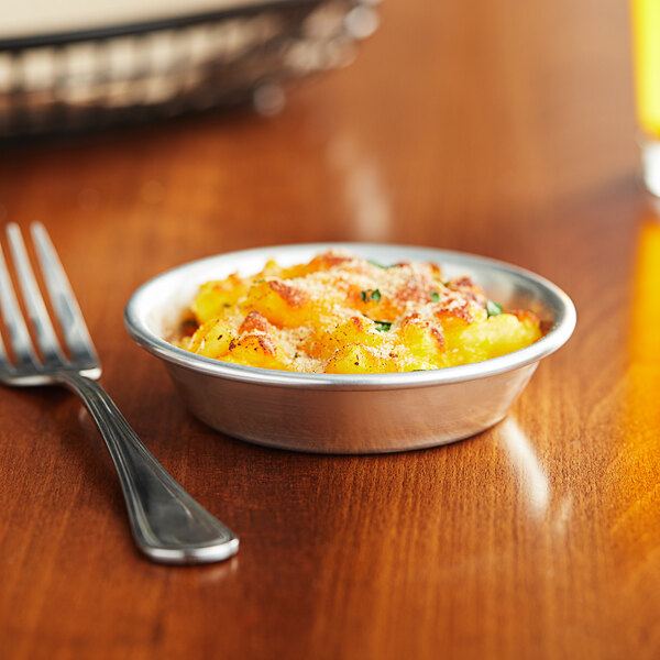 A Baker's Mark mini pie pan filled with macaroni and cheese on a table with a fork.