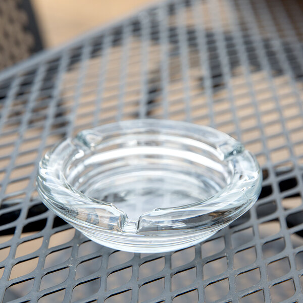 An Anchor Hocking clear glass ashtray sitting on a table.