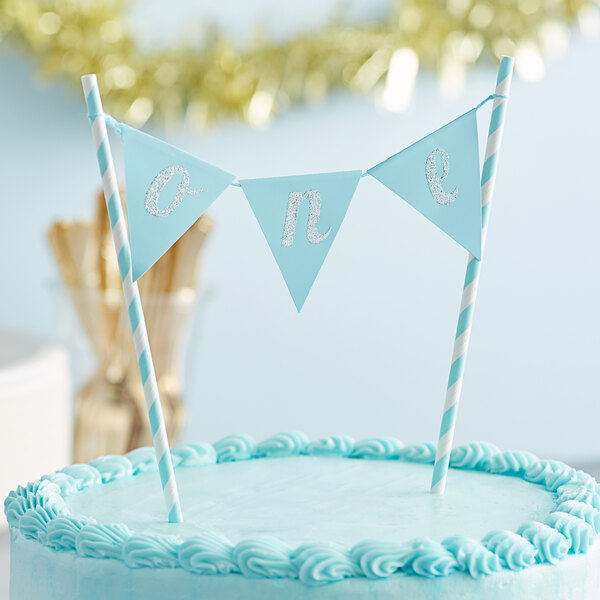 A blue cake with a blue and white "One" banner on top.