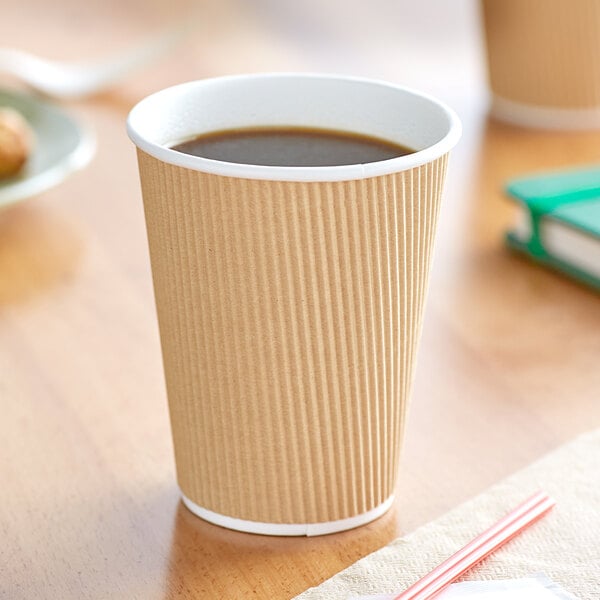 A brown paper cup of coffee sitting on a table.