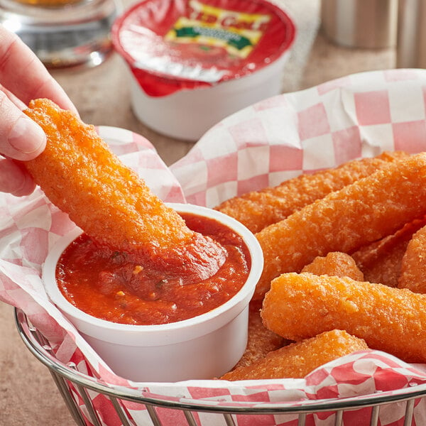 A hand dipping a fried chicken stick into a Red Gold marinara sauce cup.