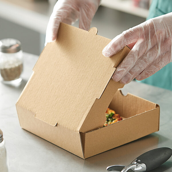 A person in gloves opening a Choice kraft cardboard pizza box.