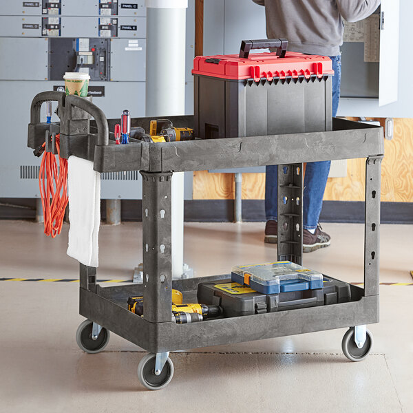 A man standing next to a Lavex black utility cart with tools on it.