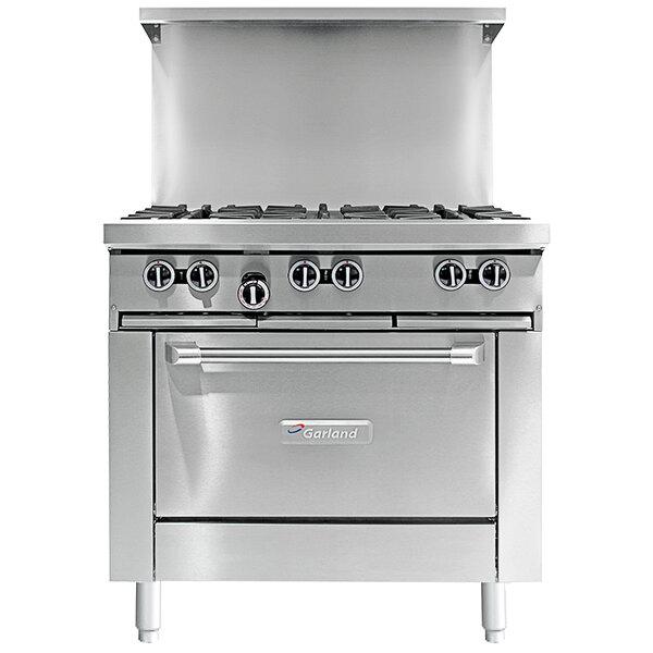 A stainless steel Garland commercial gas range with 4 burners, a griddle, and an oven with the door open.