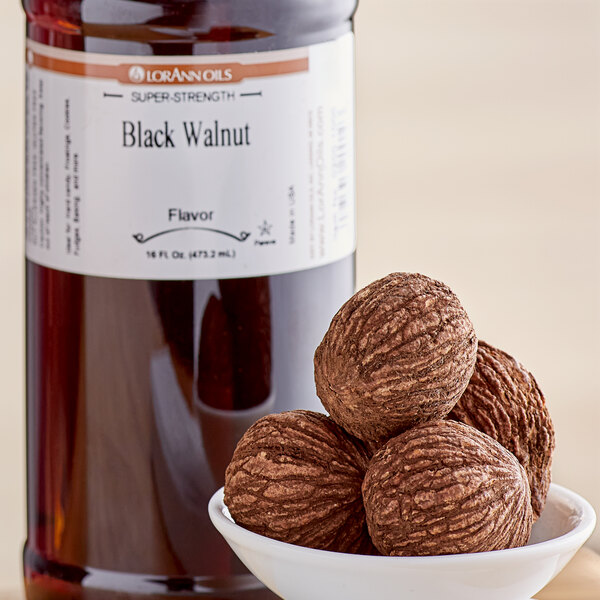 A bottle of LorAnn Oils Black Walnut Super Strength Flavor next to a bowl of nuts.