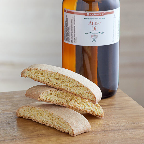 A stack of cookies on a table next to a bottle of LorAnn Oils All-Natural Anise Super Strength Flavor.
