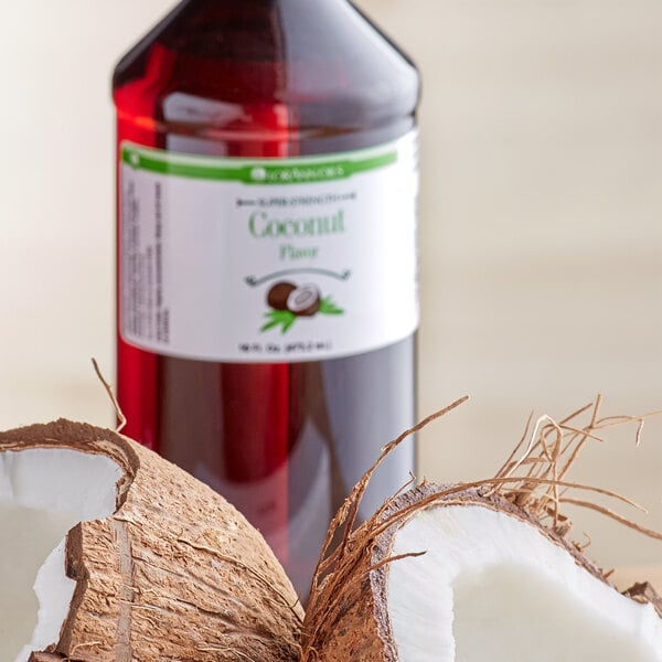A bottle of LorAnn Oils Coconut Super Strength Flavor next to a coconut with a broken shell.