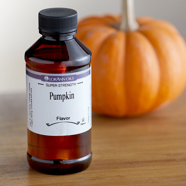 A white bottle of LorAnn Oils Pumpkin Super Strength Flavor next to a pumpkin.