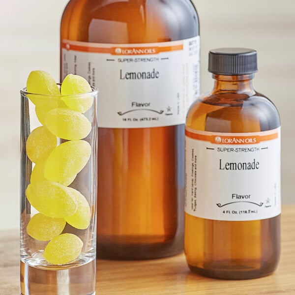 A glass of lemonade with a bottle of LorAnn Oils Lemonade Flavor on the counter.