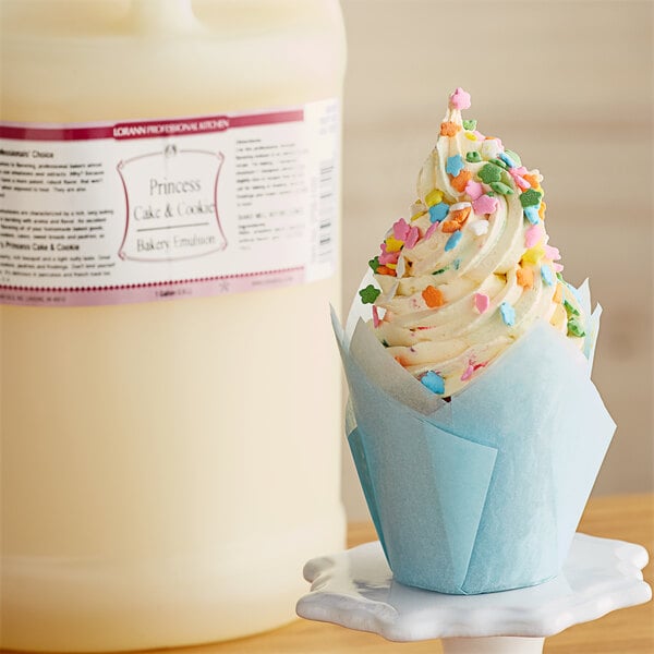 A close-up of a cupcake with white frosting and sprinkles.