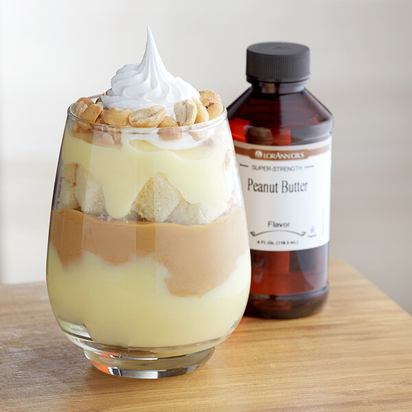 A glass of dessert with liquid and peanut butter on top.