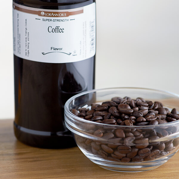 A bowl of coffee beans next to a bottle of LorAnn Oils Coffee Super Strength Flavor.