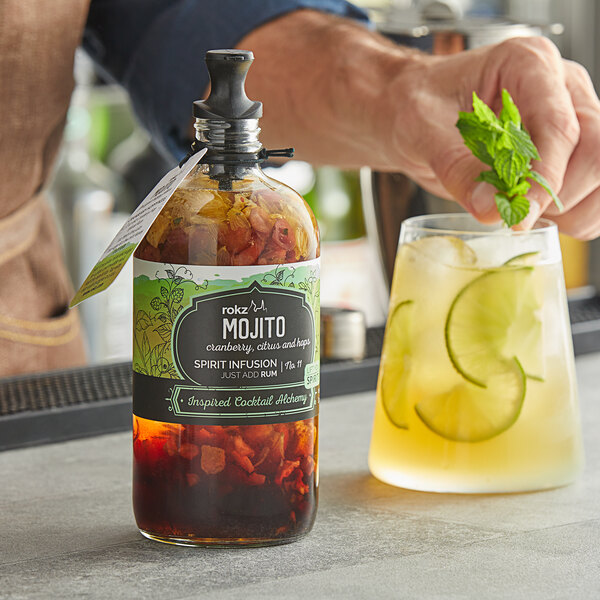 A bartender using a Rokz Mojito Cocktail Infusion Kit to make a drink with mint and lime.