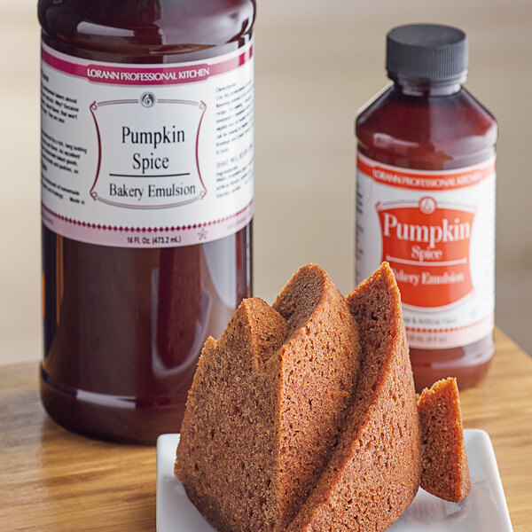 A slice of cake on a plate next to a bottle of LorAnn Pumpkin Spice Bakery Emulsion.