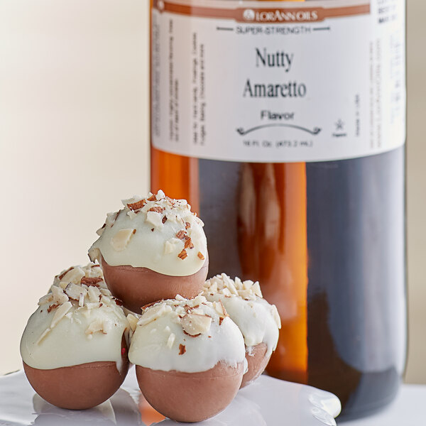 A close up of a dessert with white and brown frosting and almonds with a bottle of LorAnn Oils Nutty Amaretto flavor.
