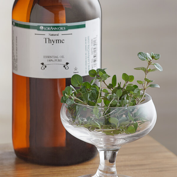 A brown bottle of LorAnn Oils All-Natural Thyme Super Strength Flavor next to a glass bowl of thyme plants.