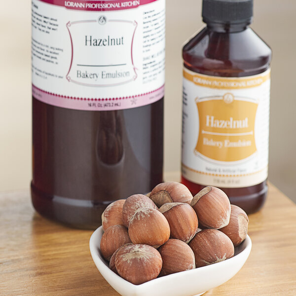 A bowl of hazelnuts next to a bottle of LorAnn Hazelnut Bakery Emulsion.