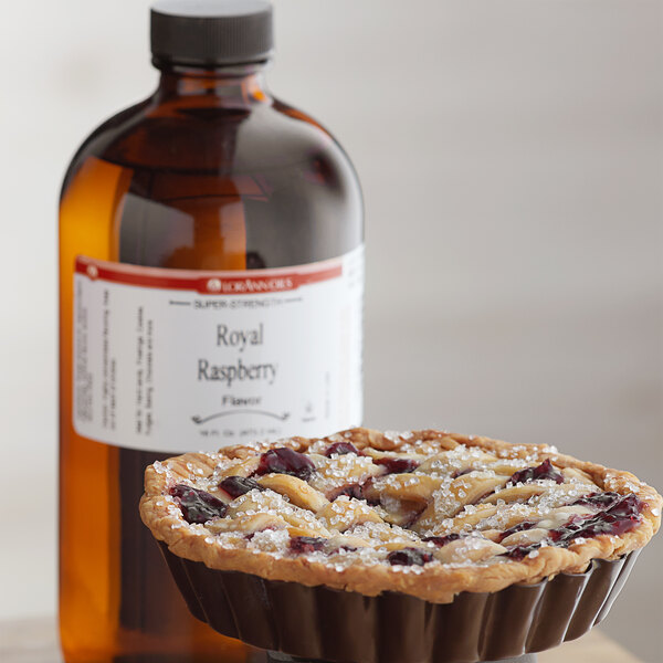 A pie with a bottle of LorAnn Oils Royal Raspberry Super Strength Flavor syrup on the counter.