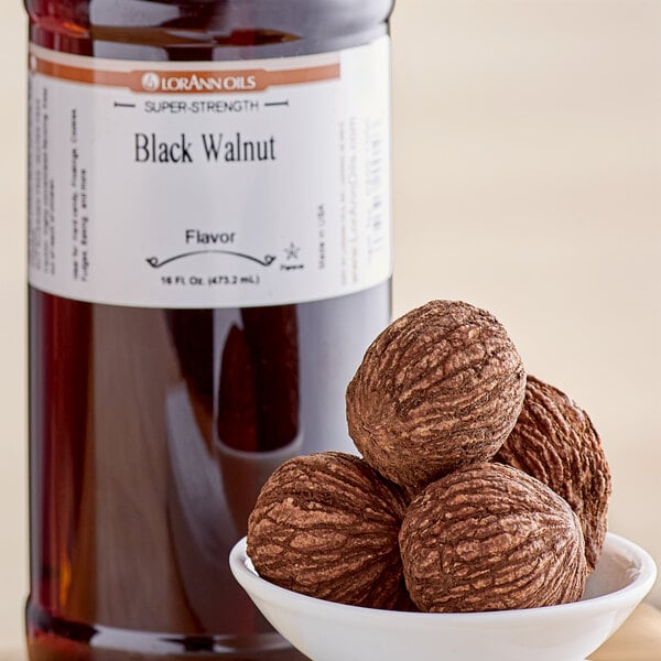 A bottle of LorAnn Oils Black Walnut Super Strength Flavor in front of a bowl of nuts.