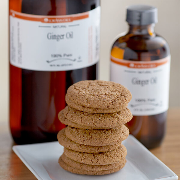 A stack of ginger cookies on a plate next to a bottle of LorAnn Oils ginger flavor.