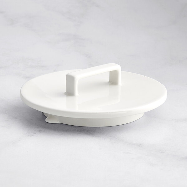 A white RAK Porcelain lid with a handle on a table.