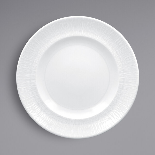 A close up of a RAK Porcelain white plate with a textured edge.