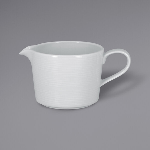 A white porcelain gravy boat with an embossed handle.