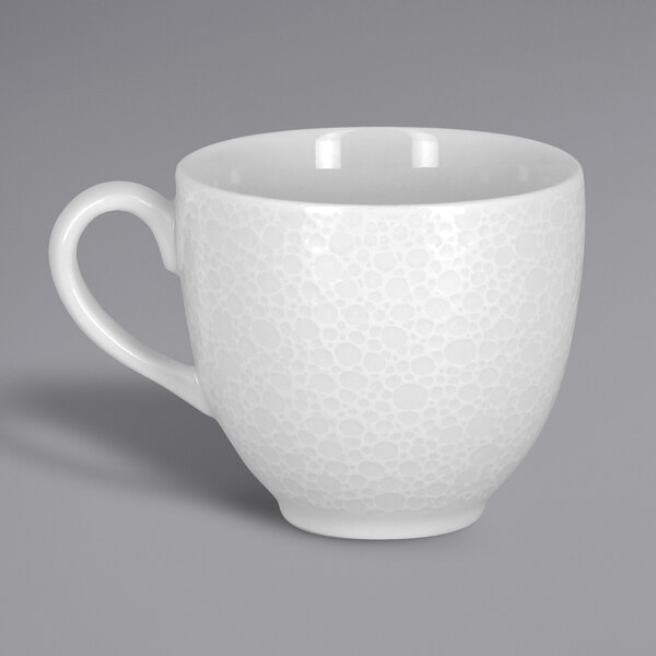 A close-up of a RAK Porcelain bright white cup with an embossed pattern.