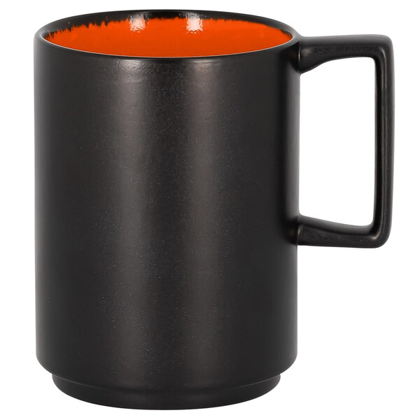 An orange porcelain RAK mug with a black handle.