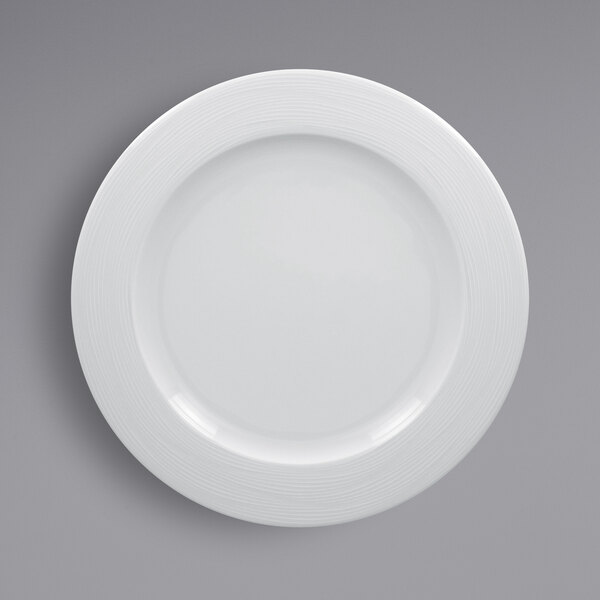 A RAK Porcelain white porcelain plate with a wide, curved rim and embossed circular pattern.