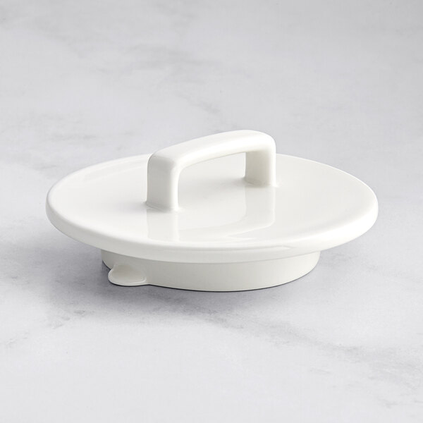 A RAK Porcelain warm white porcelain lid with a handle on a white surface.
