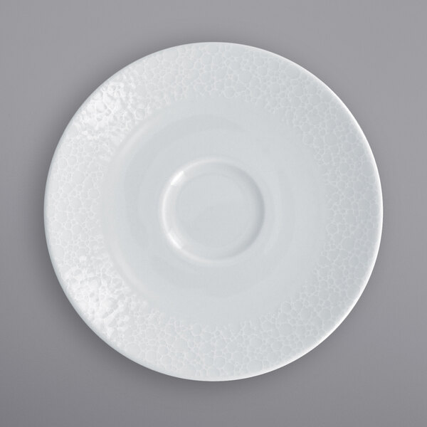 A RAK Porcelain bright white round saucer with a circular pattern in the center.