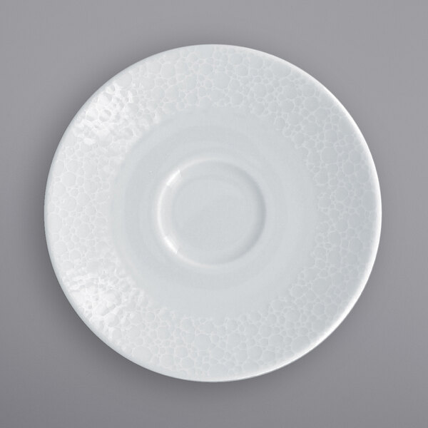 A close-up of a RAK Porcelain bright white saucer with a circular pattern.