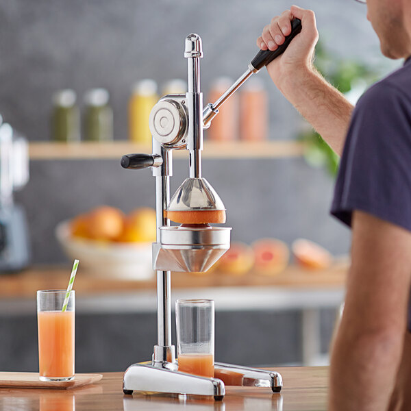 A man using a Choice Prep manual citrus juicer to make orange juice.