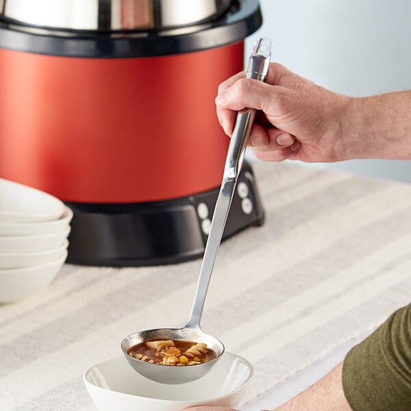 A person using a Choice stainless steel ladle to serve soup