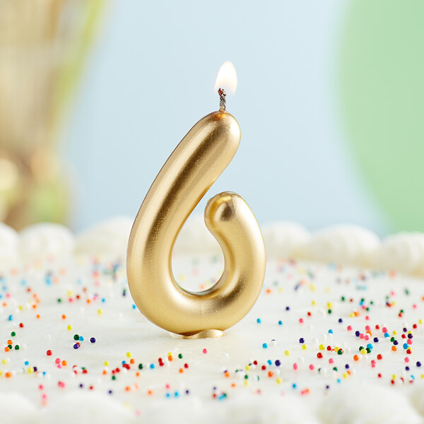 A gold "6" candle on a cake.