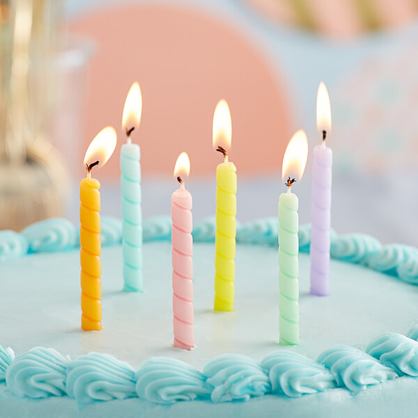 A white birthday cake with six Creative Converting assorted pastel spiral candles on it.