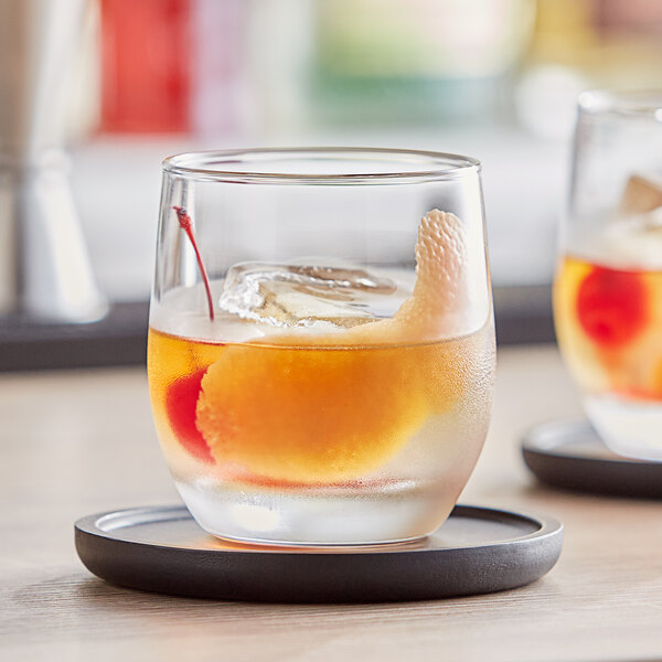 Two Pasabahce Bolero Old Fashioned glasses filled with ice, liquid, and cherries.