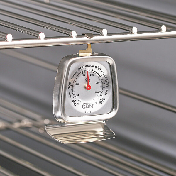 A CDN metal oven thermometer hanging on a rack.