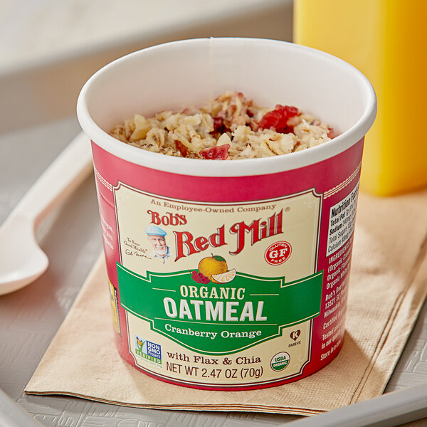 A Bob's Red Mill Cranberry Orange oatmeal cup in a bowl with a spoon.