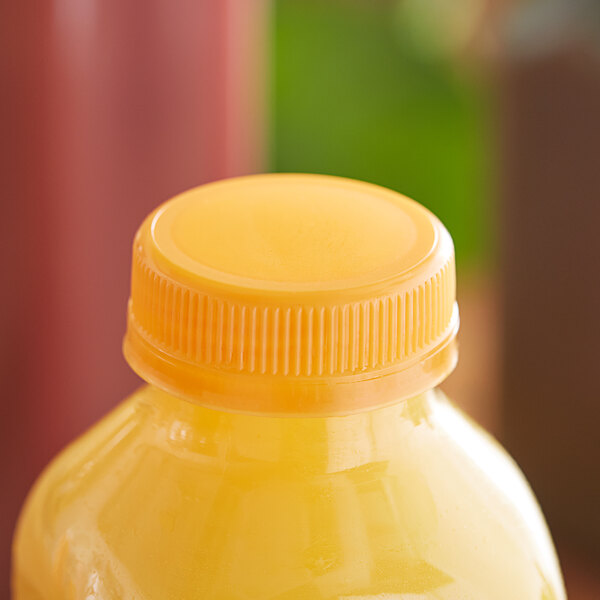 A close up of a yellow cap on a bottle of orange juice.