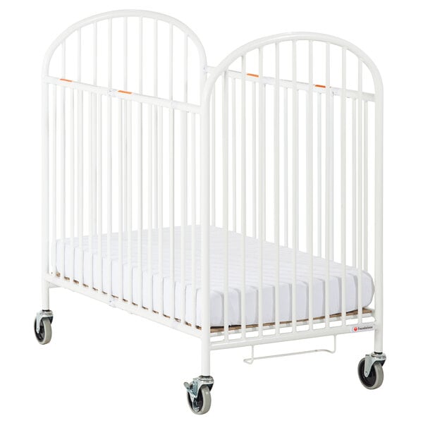 A white Foundations steel folding crib with wheels.